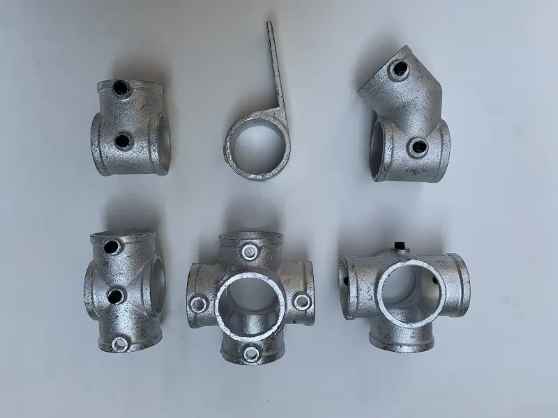 Six precision-cast structural pipe connectors used for assembling indoor playground equipment frames, arranged on a white background.