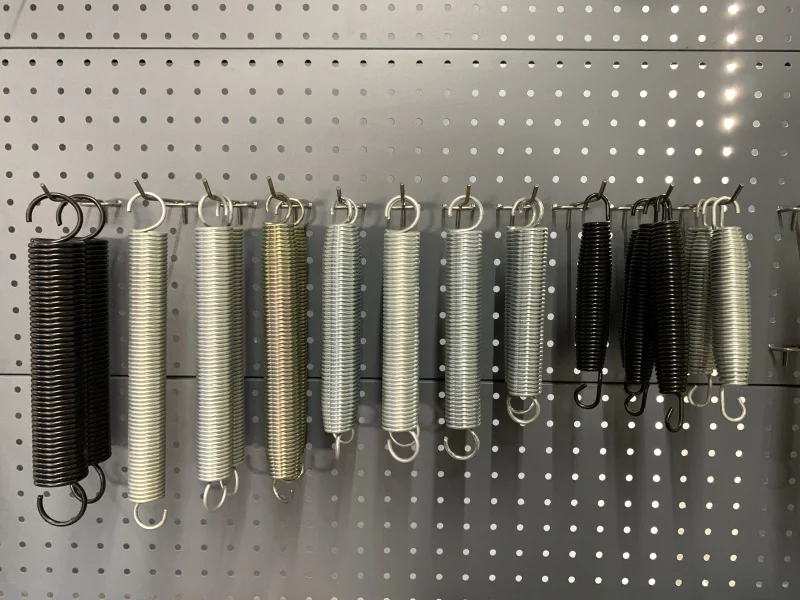 High-carbon piano wire springs for commercial trampoline parks, showing ASTM A228 trampoline spring samples with different finishes and sizes.