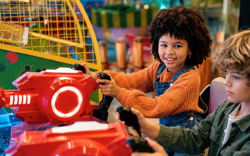 Children enjoying interactive arcade games at an indoor trampoline park, colorful play area for kids
