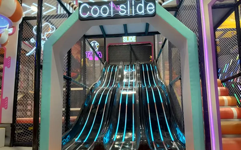 Fiberglass light slide inside a futuristic indoor playground in Alicante, Spain, featuring LED lighting effects, smooth sliding lanes, and soft landing protection.