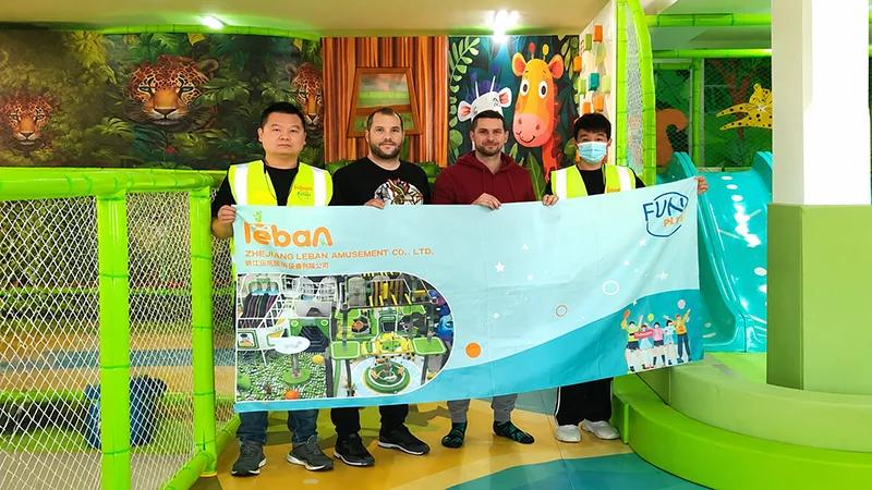Lebanplay installation team with client in completed jungle-themed indoor playground, showing vibrant play structures and safe, padded climbing areas