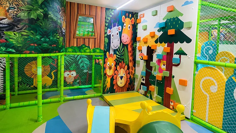 Completed jungle-themed indoor playground for children, featuring climbing walls, slides, soft play areas, and colorful animal murals