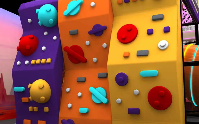 Rainbow rock climbing wall inside a futuristic indoor playground in Alicante, Spain, featuring colorful climbing panels and child-safe climbing holds.